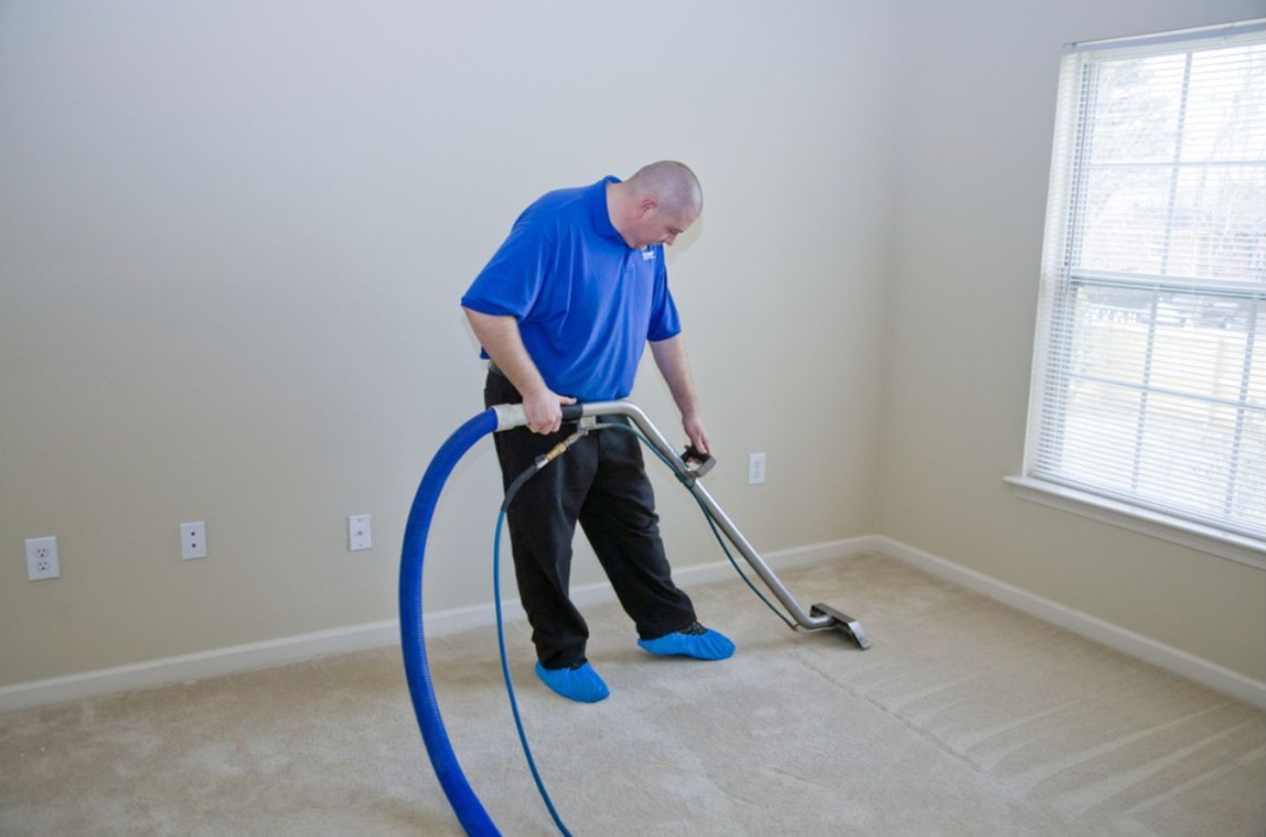 A carpet cleaner is cleaning a carpet inside a house